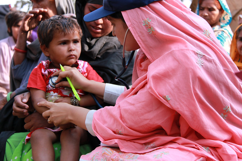 Doctor from International Medical Corp examines a young boy after flooding in Pakistan